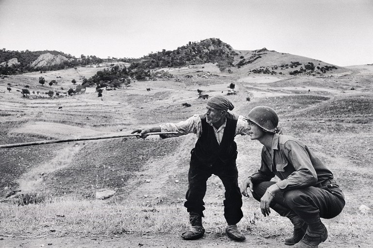 Un siciliano spiega ad un ufficiale americano quale strada hanno percorso i tedeschi vicino a Troina, Sicilia, 4 - 5 agosto 1943  © Robert Capa © International Center of Photography / Magnum Photos 