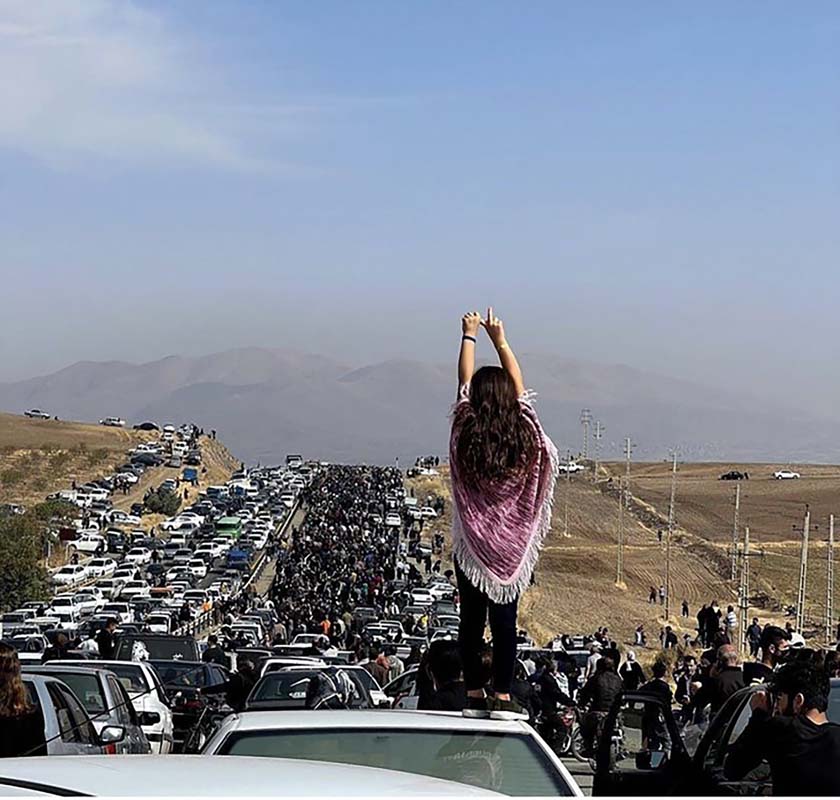 Marie Sumalla & Ghazal Golshiri, A young woman without a hijab stands on a vehicle as thousands of people make their way to the Aychi cemetery, to commemorate the 40th day of Mahsa Amini’s death, in Saqqez, her hometown in Iranian Kurdistan