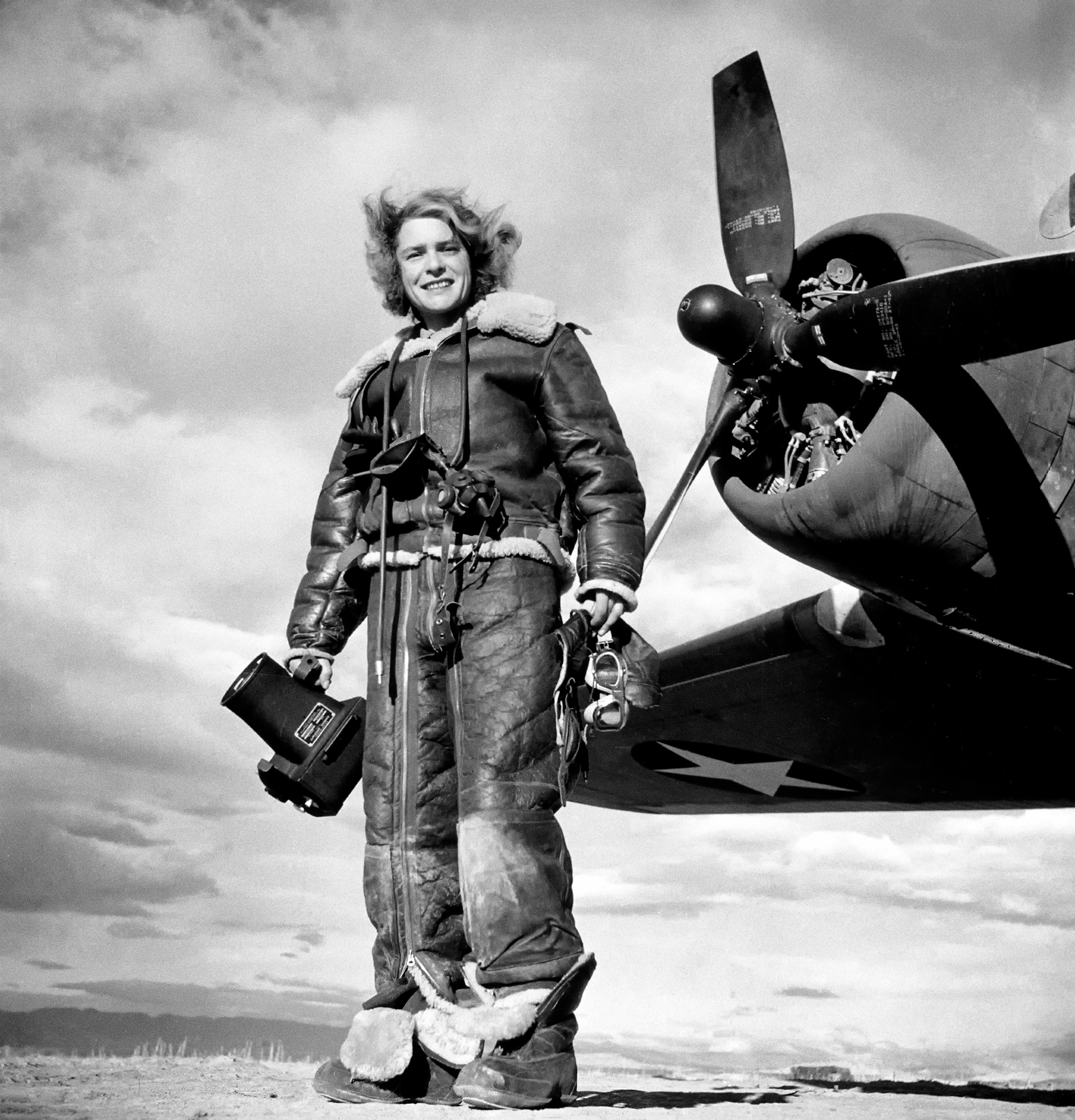 La fotografa di LIFE Margaret Bourke-White, vestita con una tuta di volo in pile e con la macchina fotografica aerea in mano, in piedi davanti al bombardiere Flying Fortress dal quale ha realizzato fotografie di guerra durante l’attacco statunitense su Tunisi. Algeria, 1943. Margaret Bourke-White/The LIFE Picture Collection/Shutterstock