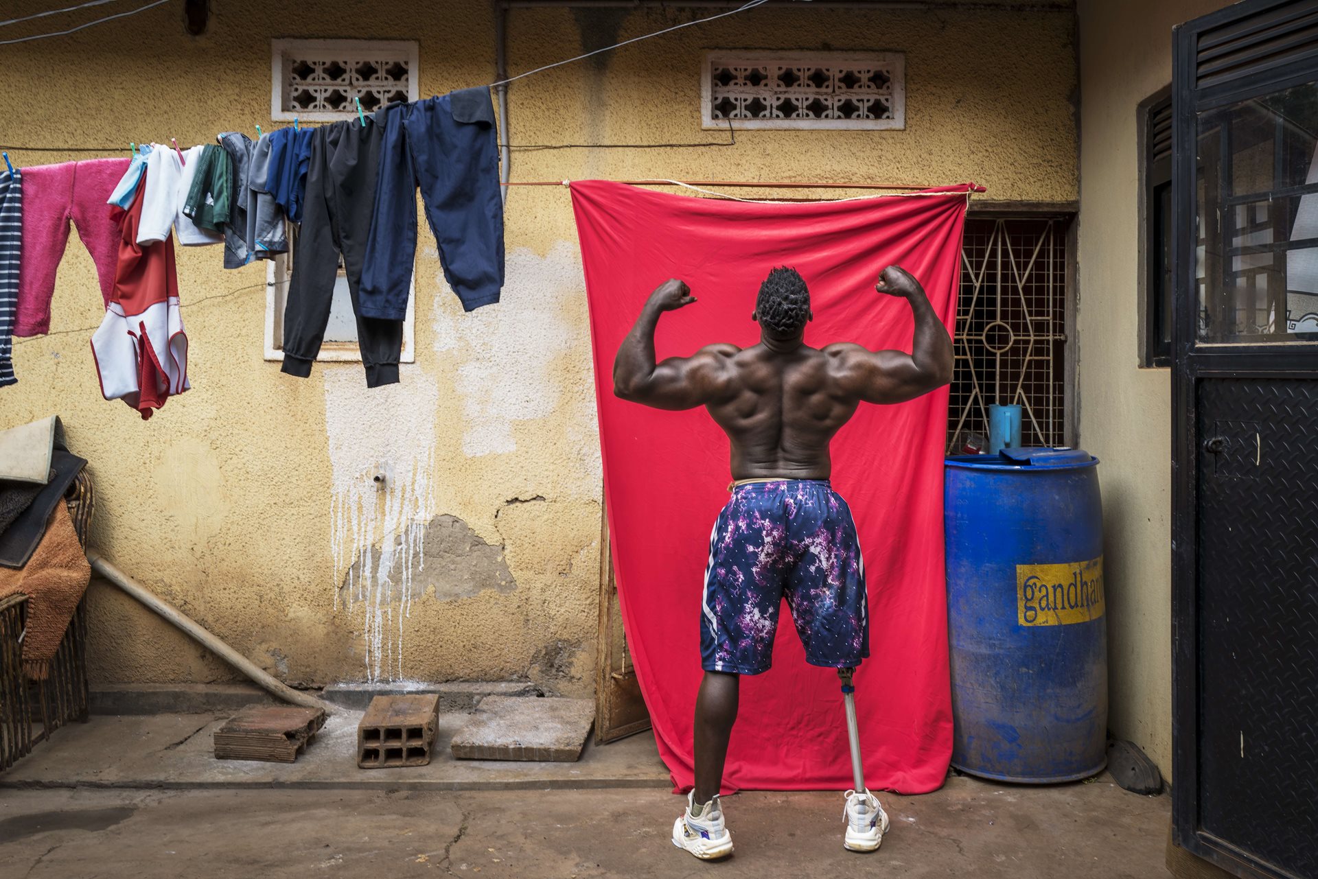 01.	Bodybuilder Tamale Safalu trains in front of his home in Kampala, Uganda (categoria Singole – regione Africa), foto di Marijn Fidder