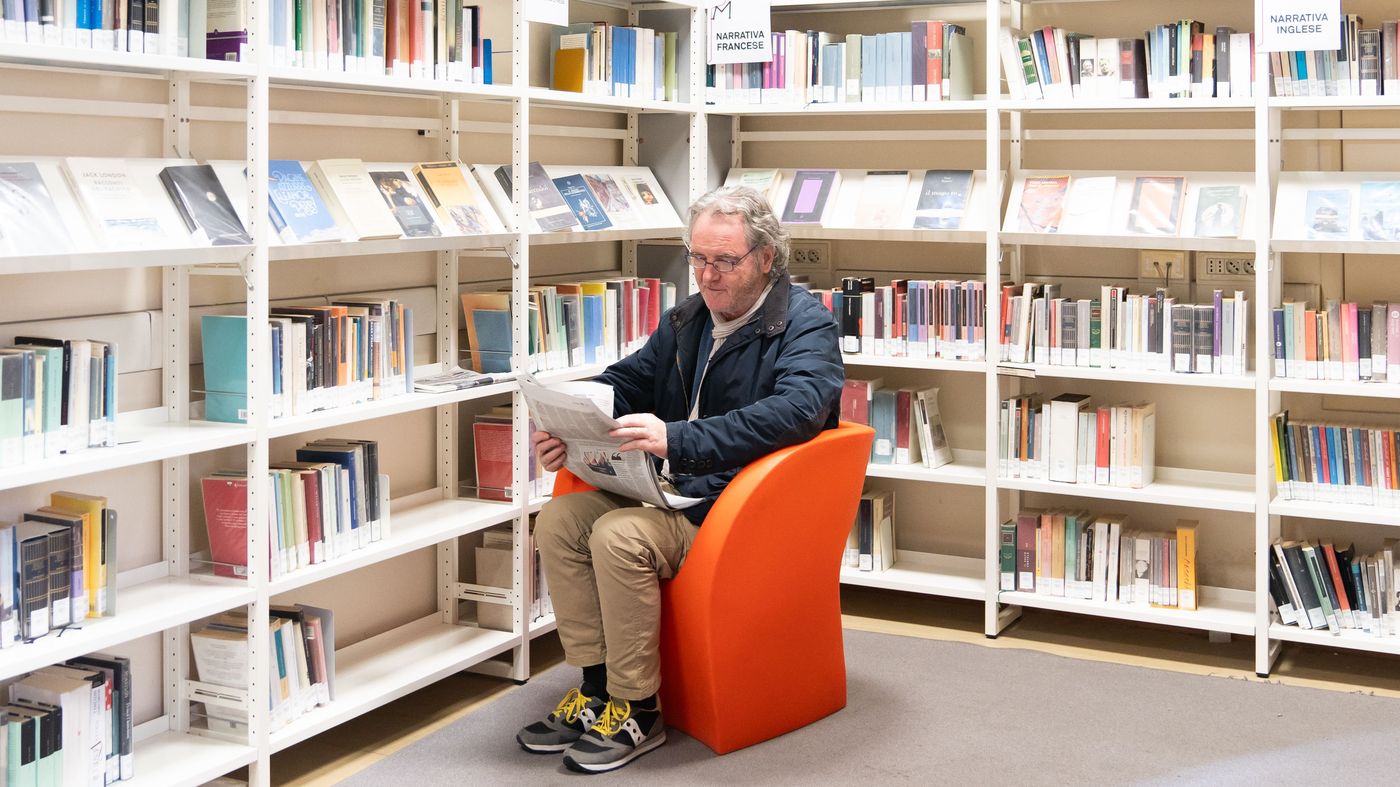 Una persona, seduta in poltrona, legge all'interno della Biblioteca Malatestiana di Cesena