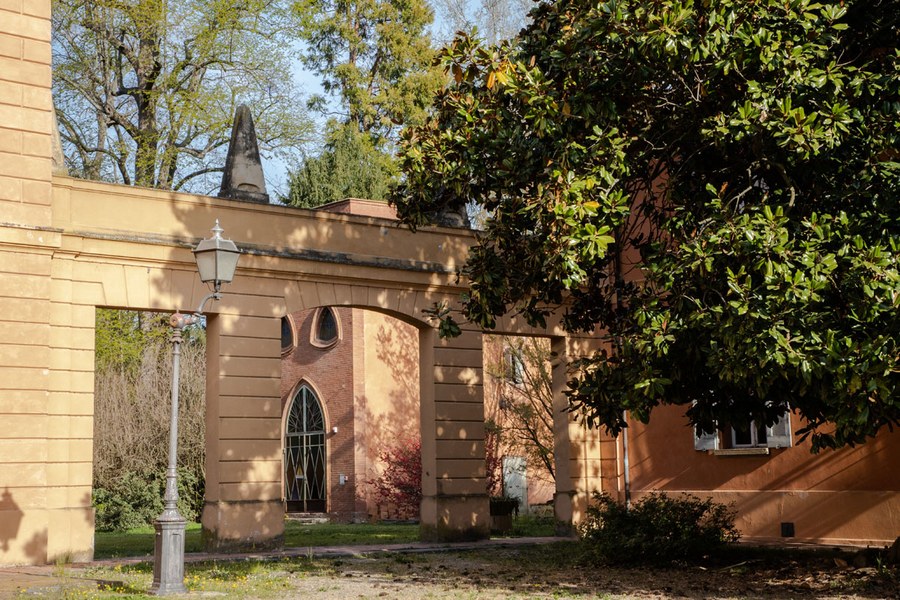 Particolare del portico che congiunge il corpo centrale con l’ala destra della Villa e sullo sfondo l’ex serra del parco (Ufficio Stampa e Comunicazione, Comune di Castel Maggiore)